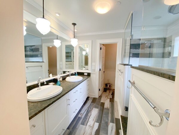A modern bathroom with two sinks, a large mirror, and a glass shower enclosure.