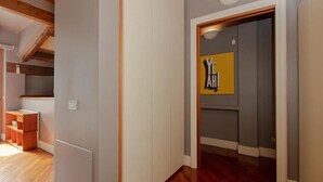 Un couloir doté d’un plancher en bois, d’une porte blanche et d’un panneau jaune avec du texte noir.
