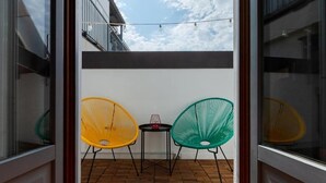Un balcon avec deux chaises et une petite table, une vue dégagée sur le ciel et un sol en briques.