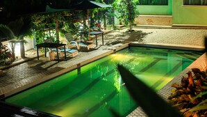 A swimming pool with a tiled deck, surrounded by potted plants and a covered seating area. - victoria view boutique hotels and tours (Kampala)