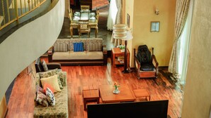 A spacious living area with a curved staircase, a sofa set, a dining table, and a wooden floor. - victoria view boutique hotels and tours (Kampala)