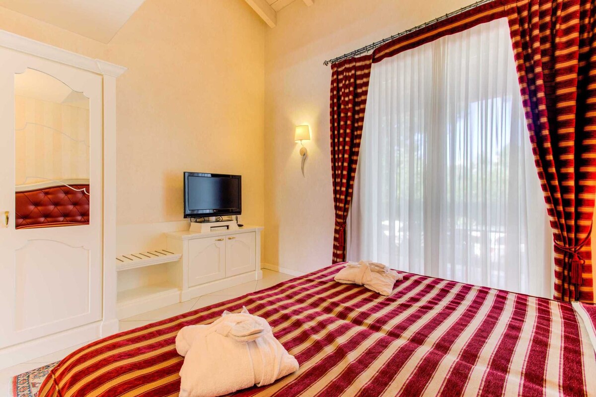 Ein Hotelzimmer mit Bett, Fernseher, Kleiderschrank und einem fenster mit Vorhängen.