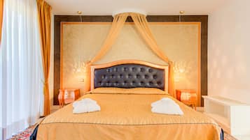 Ein Hotelzimmer mit einem großen Bett, einem Baldachin, zwei Nachttischen und einem Beistelltisch.