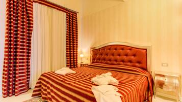 Een hotelkamer met een groot bed, strepenbeddengoed, een gestapeld hoofdbord, een nachtkastje en een bedtafel.