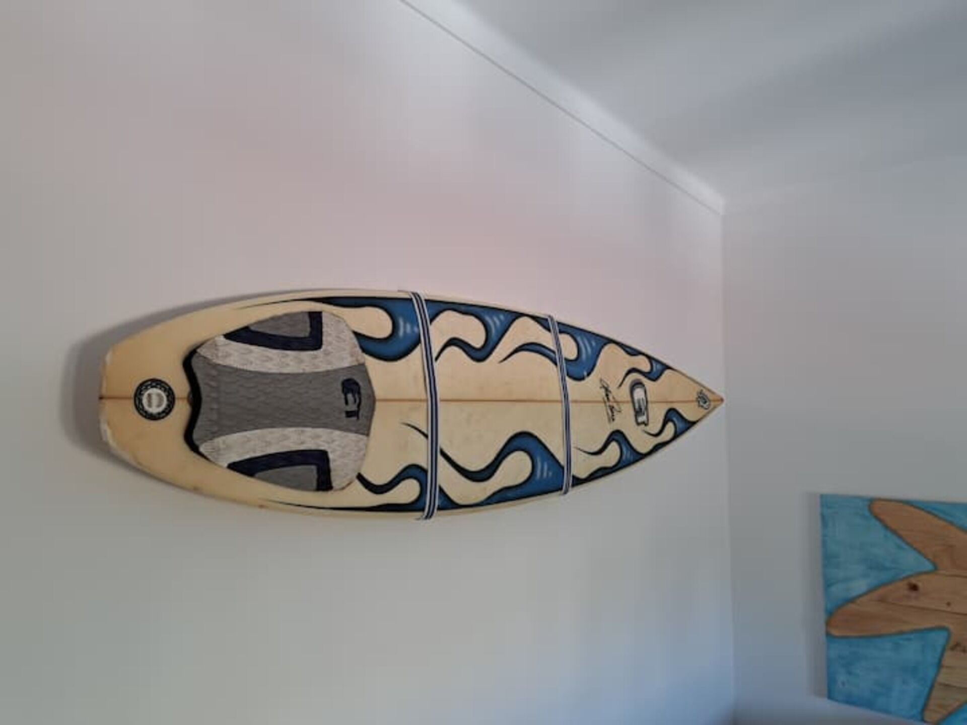 A wall-mounted surfboard decoration with a wave design.