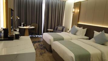 Una habitación de hotel con dos camas, un escritorio, una silla y una mesita.