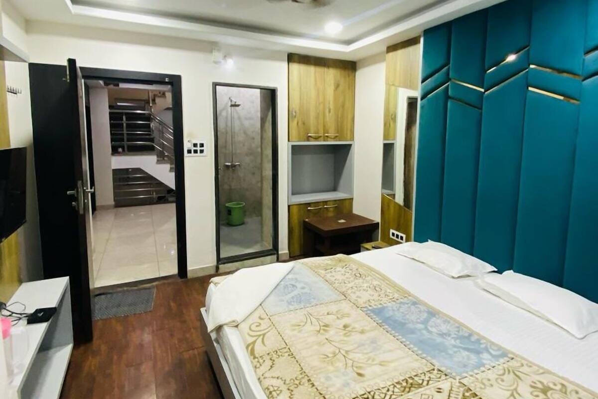A bedroom with a bed, a wardrobe, a desk, and a mirror.
