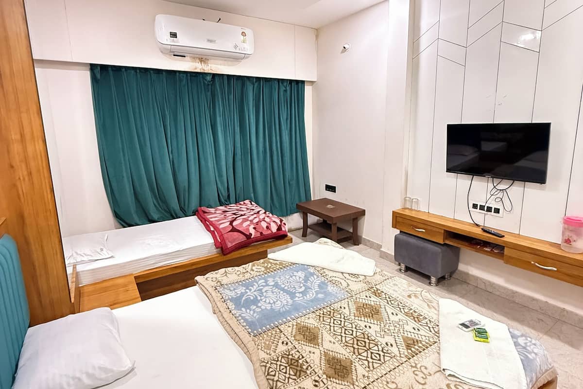 A modern bedroom with a bed, a TV, an air conditioner, and a ceiling fan.