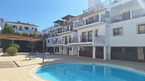 A multi-story residential building with a swimming pool, balconies, and a covered patio area. - Paramount Gardens Resorts C201 (Tersefanou)