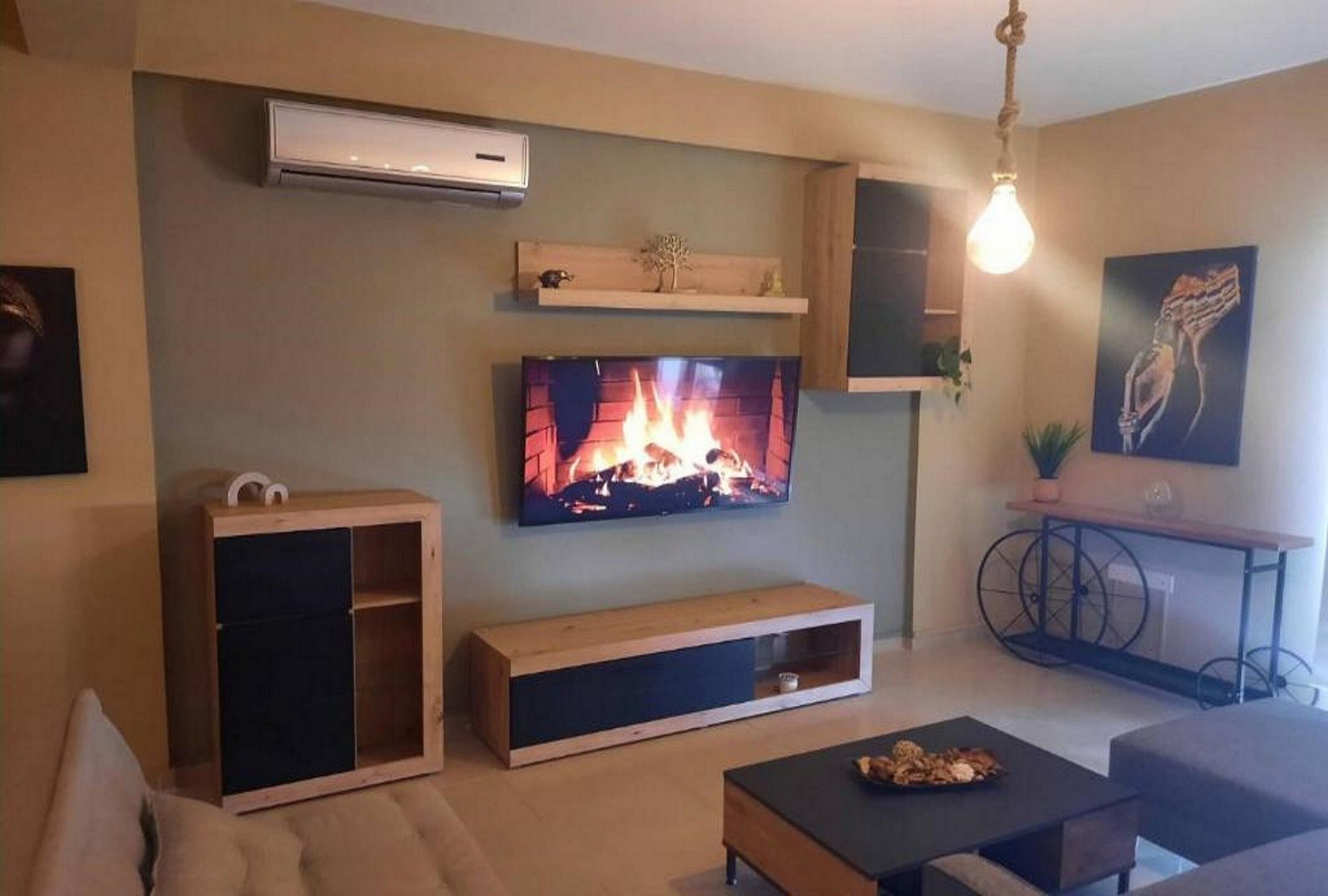 Una sala moderna con un televisor de pantalla plana, un mueble de madera para entretenimiento, un banco y una mesa de centro.