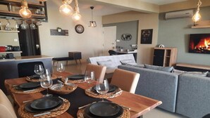 A modern living room with a dining area set for a meal. - Paramount Gardens Resorts C201 (Tersefanou)