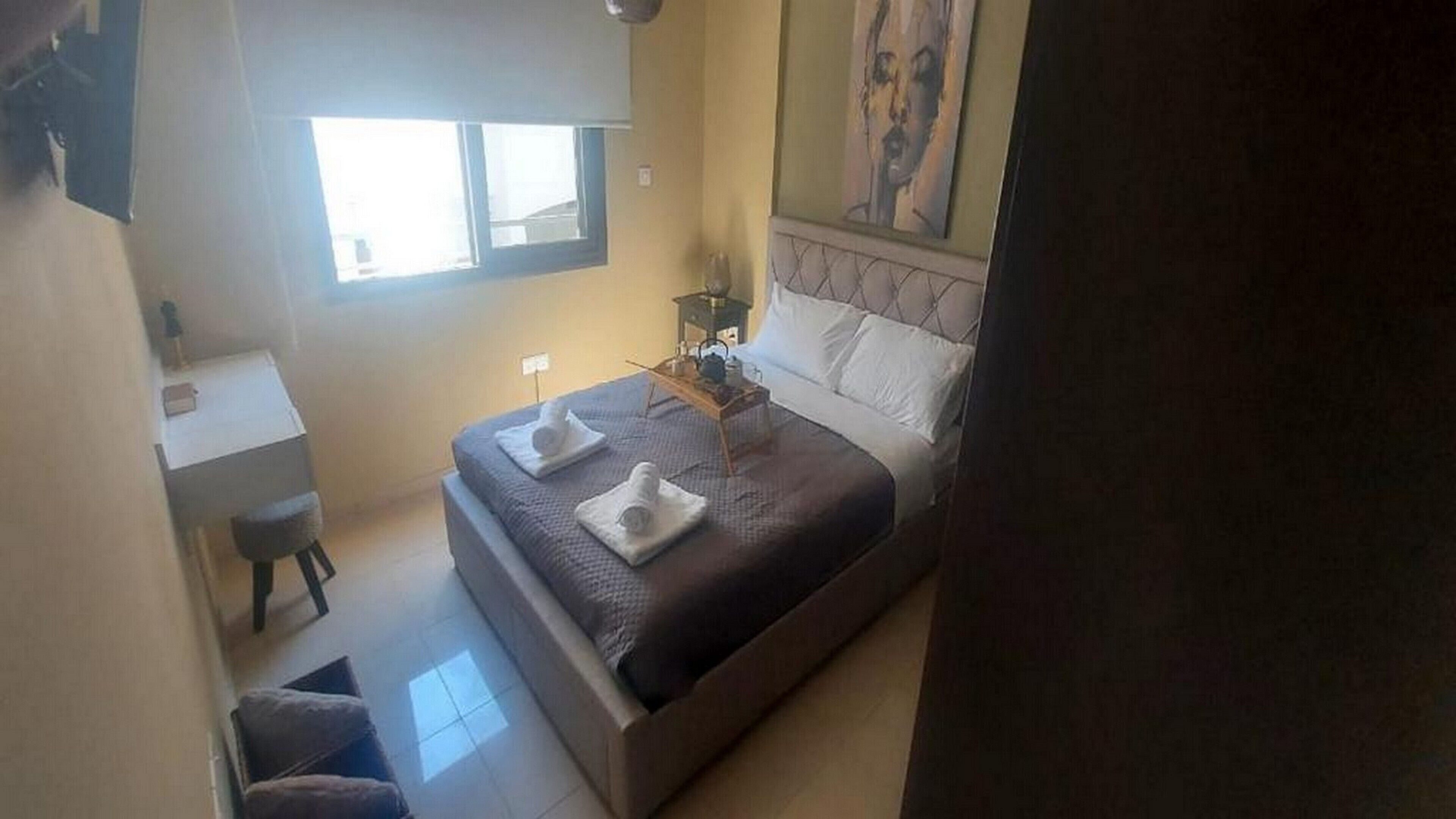 Un dormitorio con cama, mesita de noche y ventana.