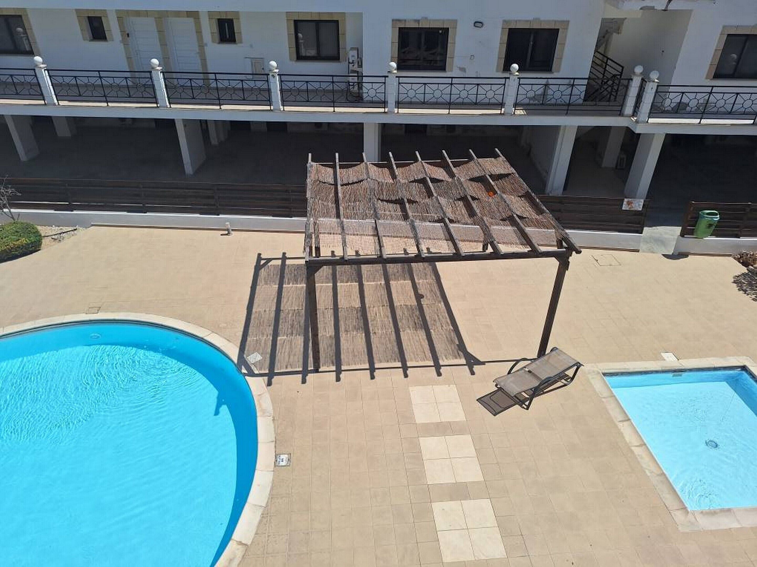 A rooftop pool area with a pergola, two lounge chairs, and a small pool.