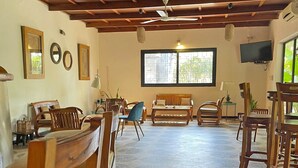 A spacious room with wooden furniture, a large window, and a ceiling fan.