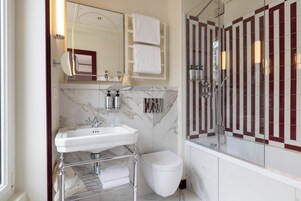 A modern bathroom with a marble sink, a toilet, and a glass-enclosed shower.