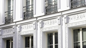 A building facade with ornate white architectural details, multiple windows, and black wrought iron balconies. - Hôtel Filigrane & Spa (Paris)