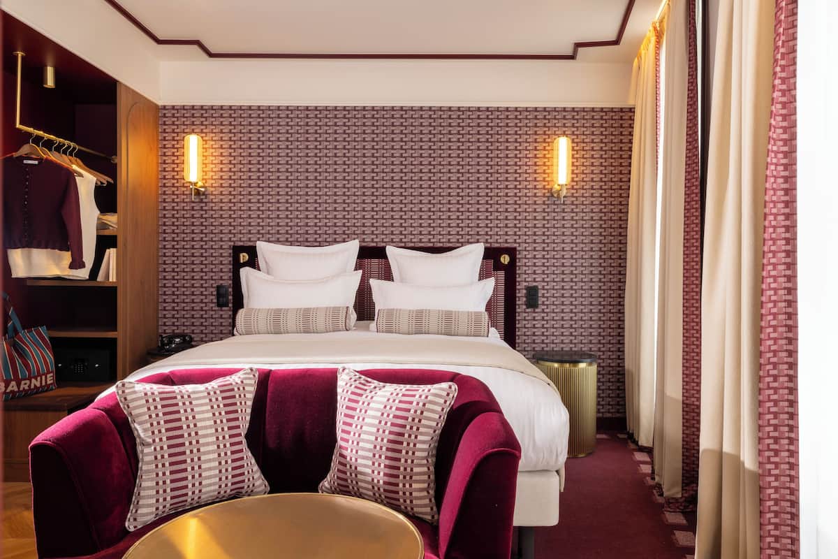 Una habitación de hotel con una cama grande, un armario y una zona de estar.