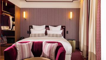 A hotel room with a large bed, a wardrobe, and a seating area.