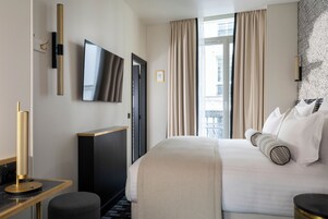 A hotel room with a bed, a desk, a TV, and a window with curtains.
