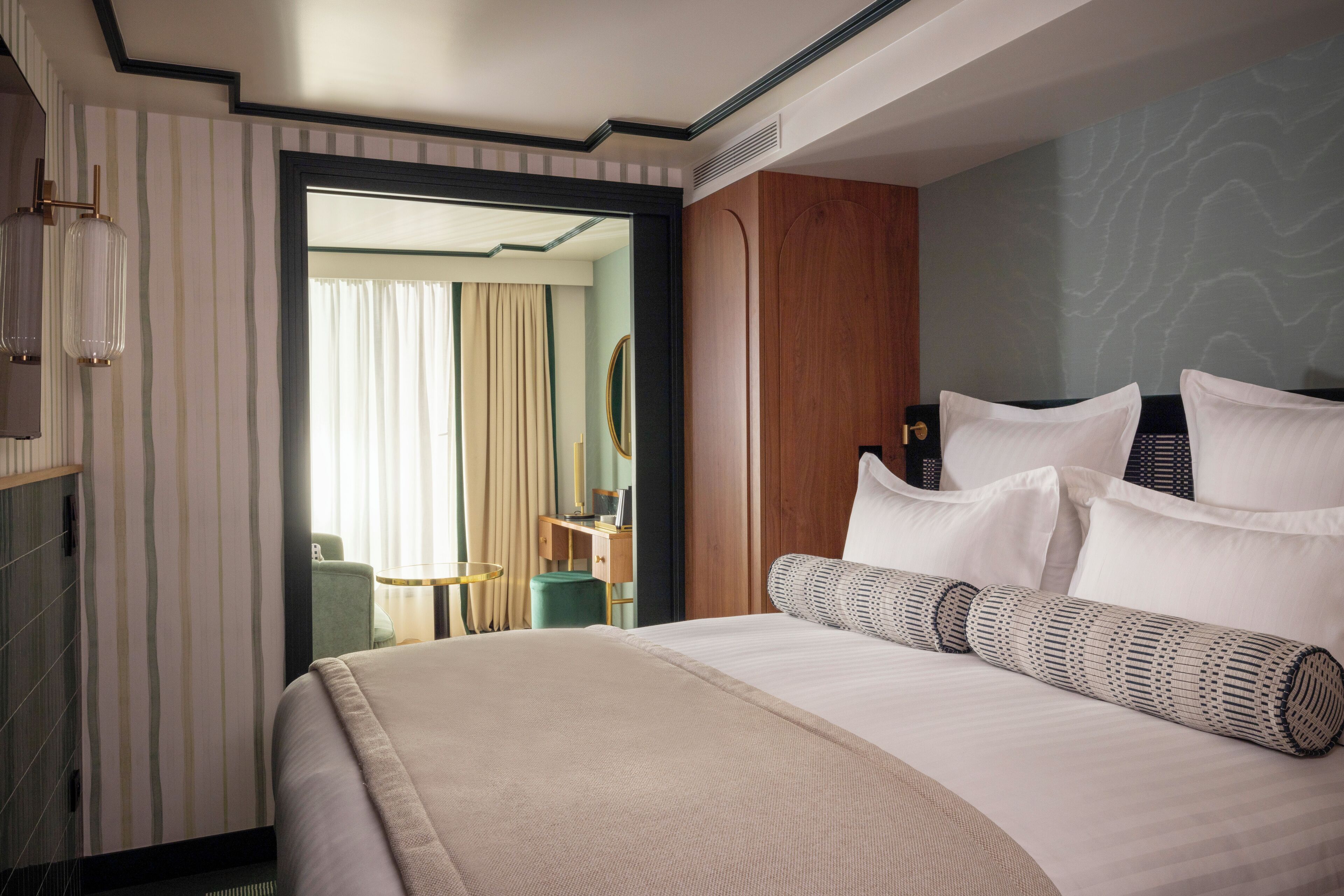 Habitación de hotel con una cama grande, un armario de madera y vistas a un balcón con cortinas.