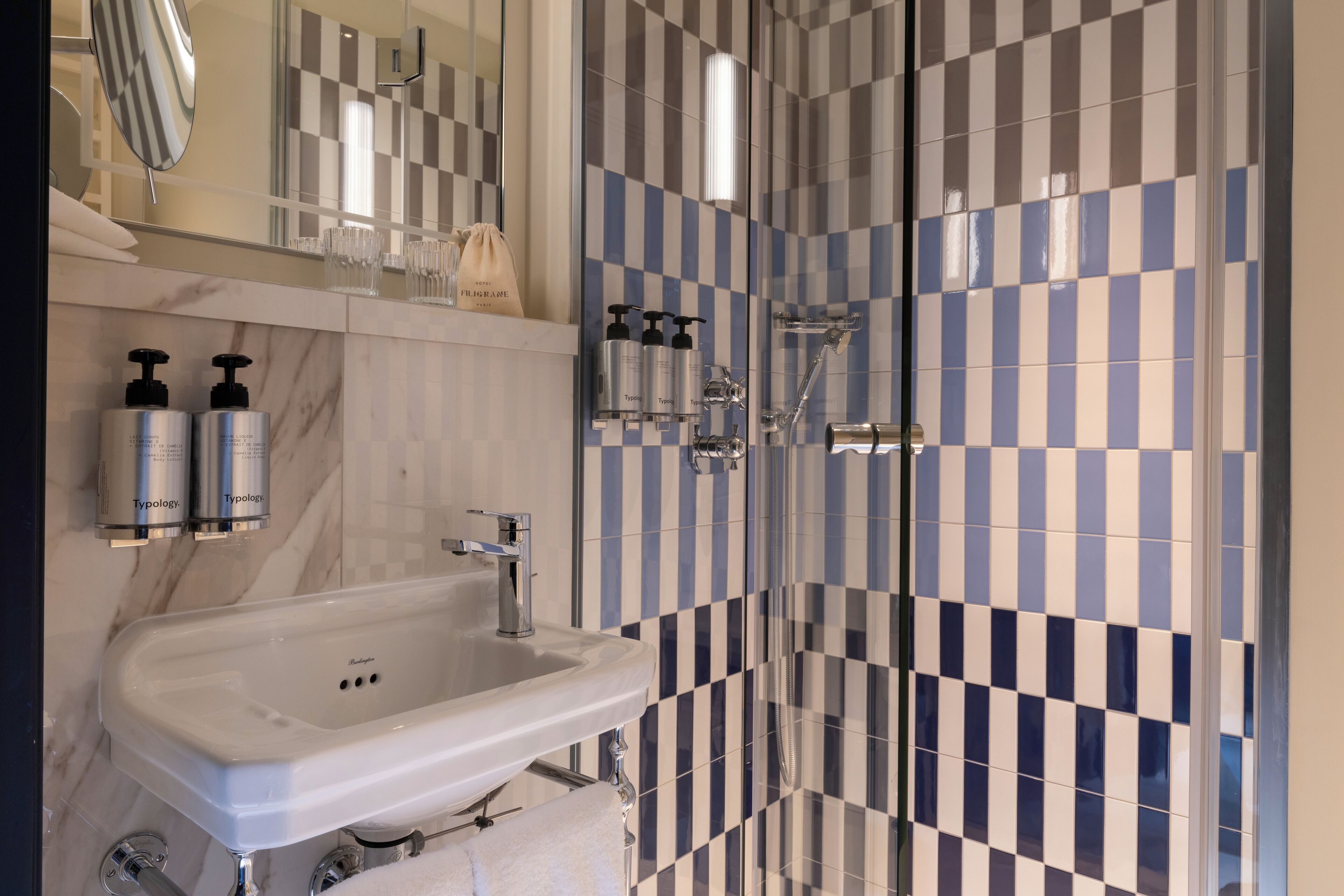 A bathroom with a white sink, mirror, and two bottles of Typology soap.
