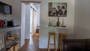 A kitchen with a TV, a dining area with a table and chairs, and a hallway leading to another room.