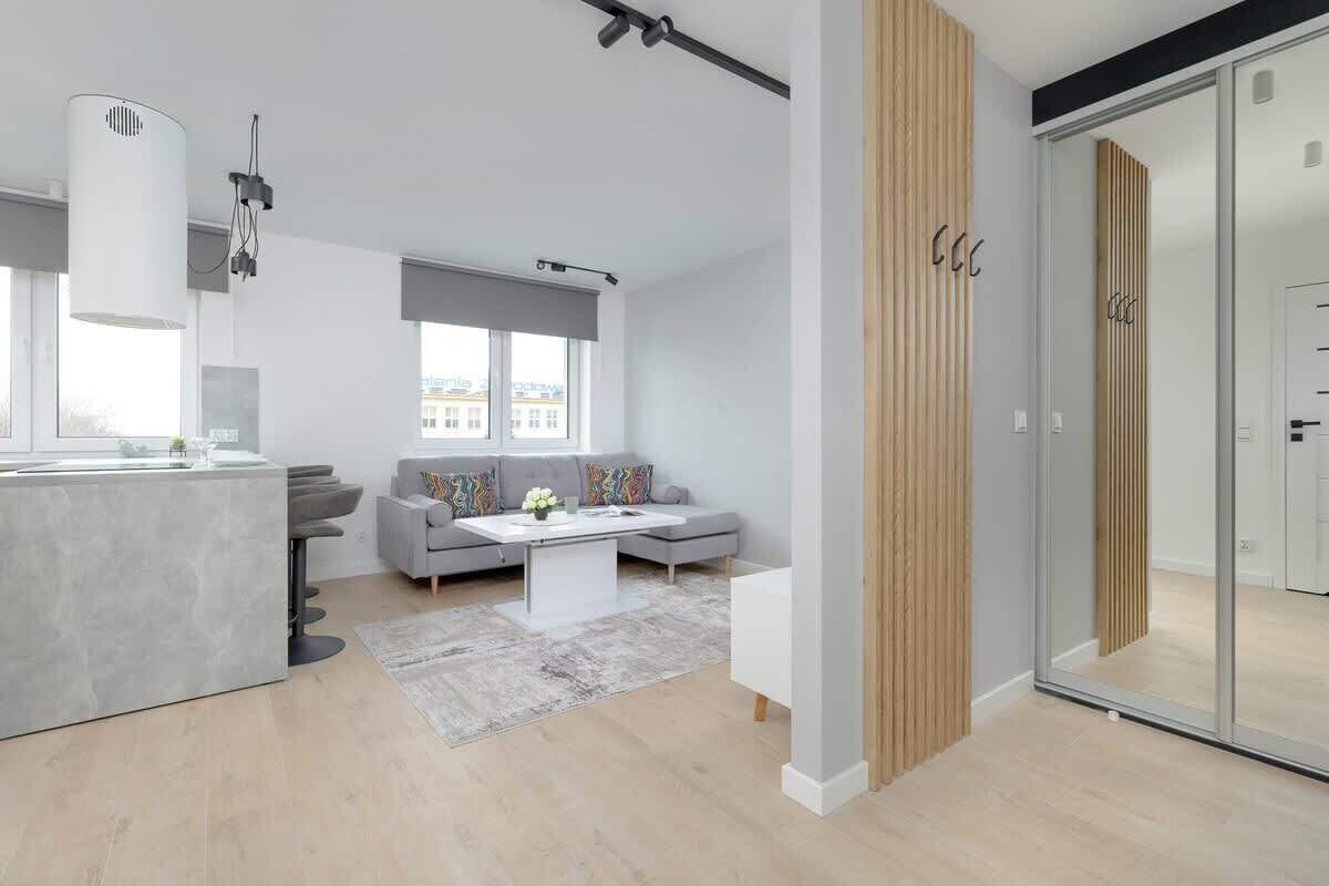 Un espacio habitable moderno con cocina, sofá gris y un amplio ventanal.