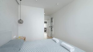 Un dormitorio moderno con cama, mesita de noche y lámpara colgante.