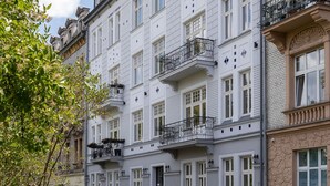 Eine Reihe mehrstöckiger Gebäude mit Balkonen, parkierten Autos und blauem Himmel.