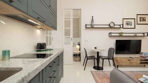 Eine moderne Küche mit Einbauherd, ein Essbereich mit Fernseher und ein Wohnzimmer mit Sofa.