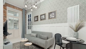 A modern living room with a grey sofa, a round coffee table, and a dining area with a glass table and chairs.