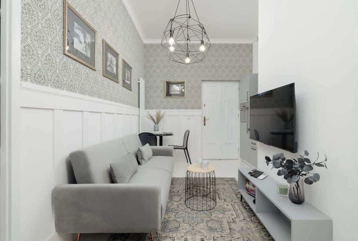 A modern living room with a grey sofa, a round coffee table, a flat-screen TV, and a decorative plant.