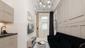 A compact kitchen with a modern design, featuring a built-in oven, a sink, and a flat-screen TV mounted above the counter. - Tasteful Apartment with Balcony | Air Conditioning | Close to the Center (Kraków)