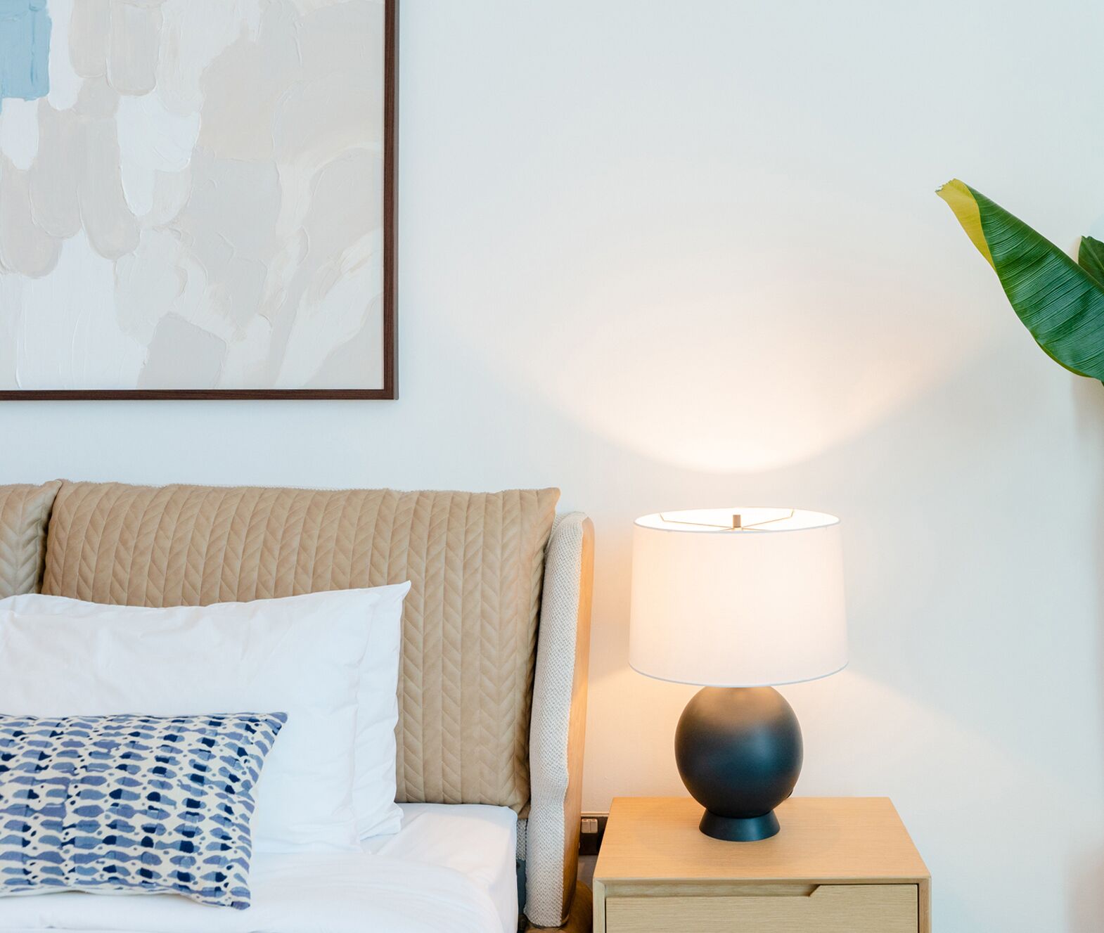 Een keurig opgemaakt slaapkamer met een bed, een bedlampje en een nachtkastje.