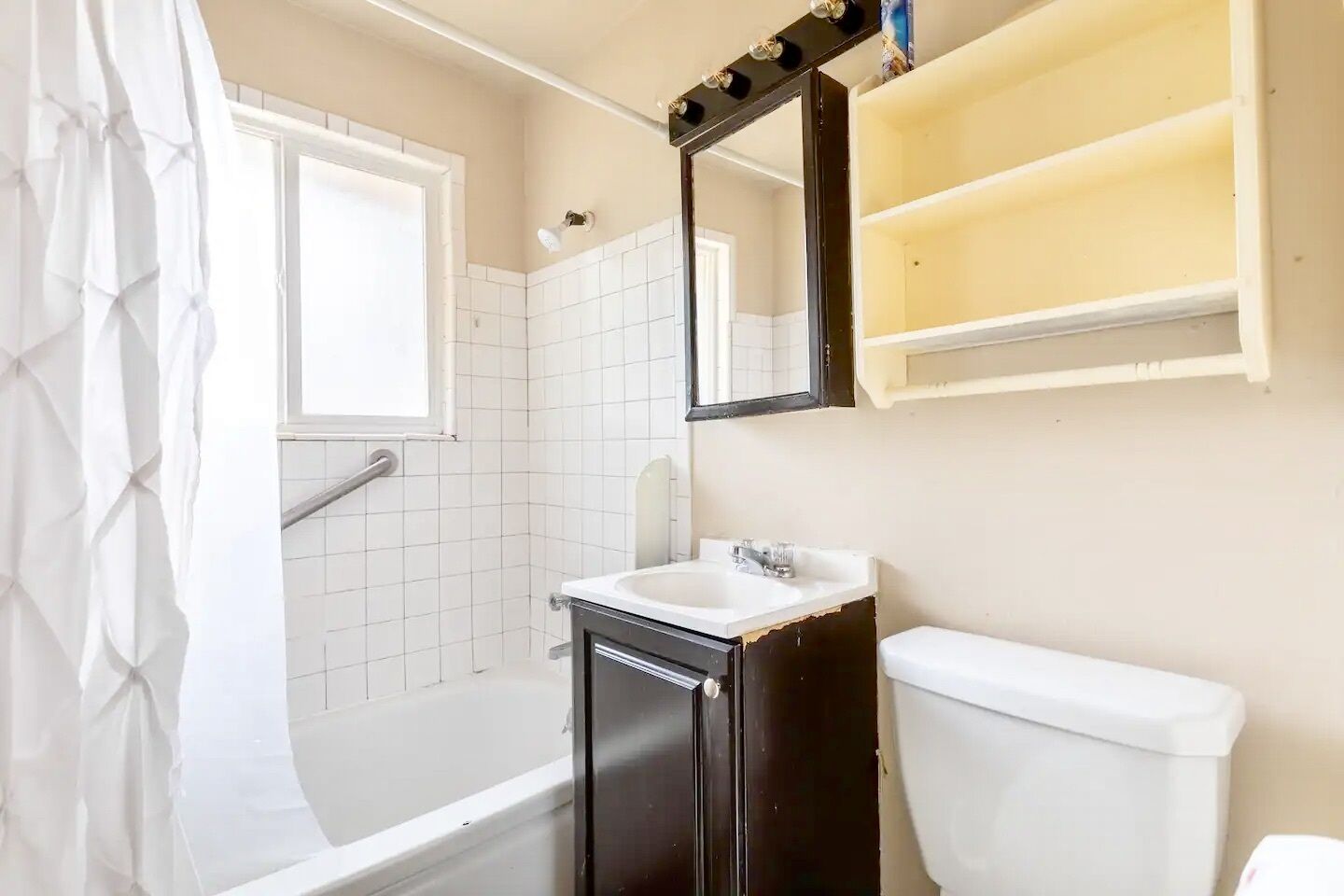 A bathroom with a bathtub, a sink, a toilet, and a mirror.