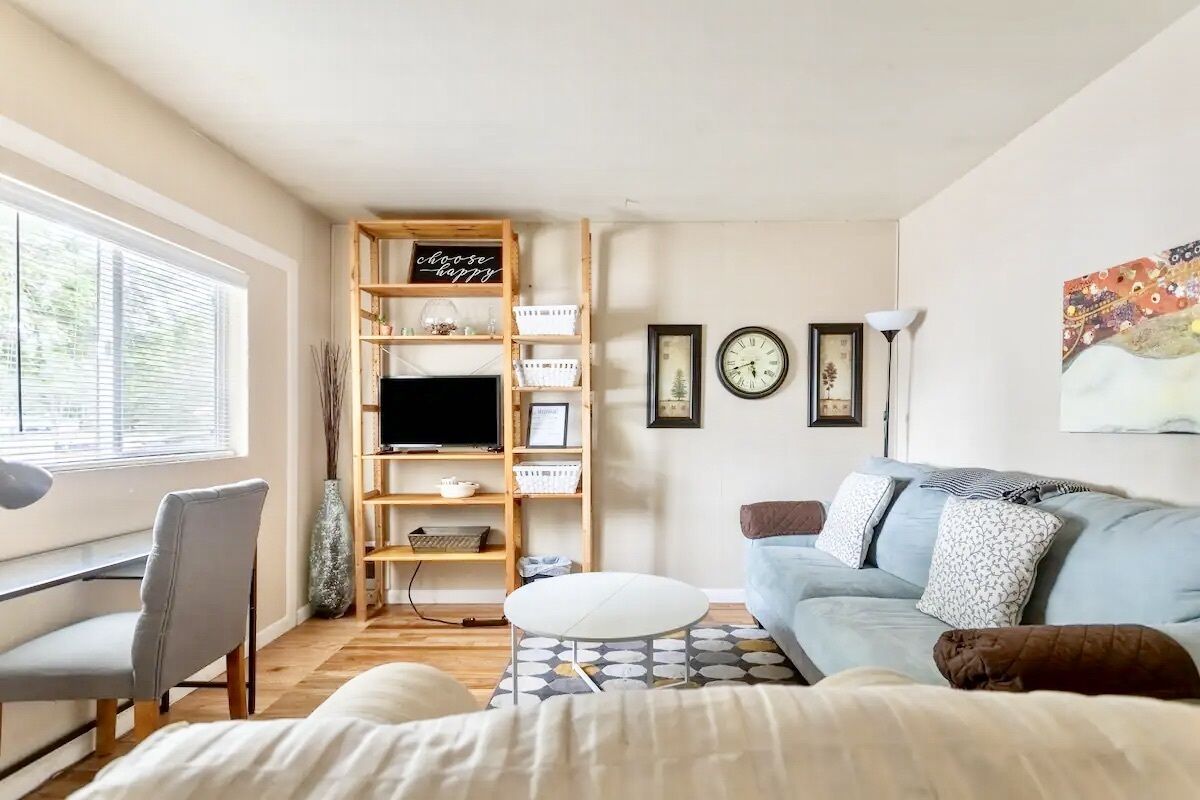 A modern living room with a sofa, a desk, a TV, and a bookshelf.