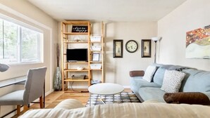 Ein modernes Wohnzimmer mit einer Couch, einem Schreibtisch, einem Fernseher und einem Bücherregal.