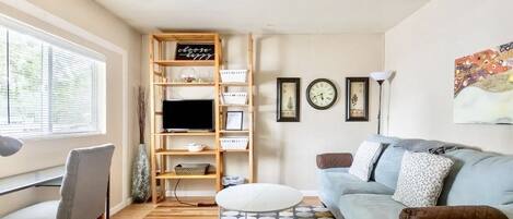 A modern living room with a sofa, a desk, a TV, and a bookshelf.