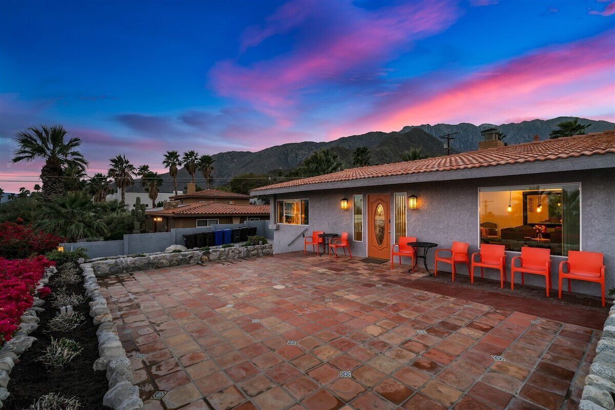 A patio area with stone tiles, outdoor seating, and a view of mountains.