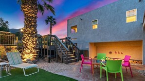 A modern house with a patio area featuring outdoor furniture, a staircase, and a pool.