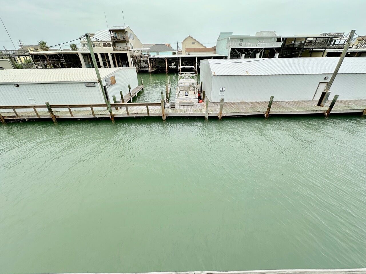 A waterfront dock with a boat moored at the pier, surrounded by buildings with a mix of commercial and residential structures.