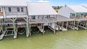 A waterfront property with multiple levels, including a balcony and a covered area with seating.