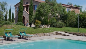 A stone villa with a swimming pool, two lounge chairs, and a stone staircase leading to a door. - Borgo Tignano (Volterra)