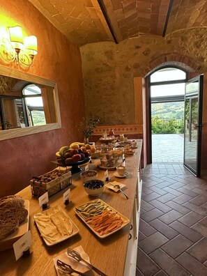 Ein reichhaltiges Frühstücksbuffet mit Speisen und Blick ins Freie.