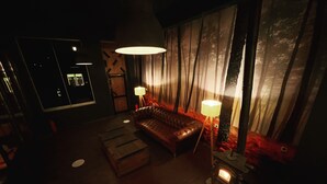 Una habitación tenuemente iluminada con un sofá de cuero, una lámpara de pie y una estufa de leña.
