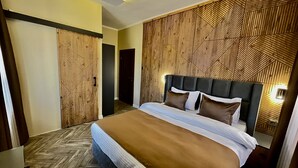 Una habitación de hotel moderna con una cama grande, un panel de pared de madera y un patrón de suelo en espiga.