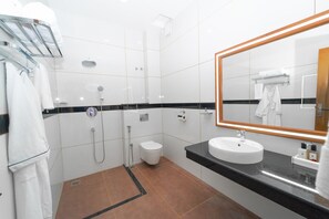 A modern bathroom with a white sink, a large mirror, and a shower area.