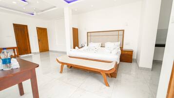 Habitación de hotel moderna con una cama grande, mesitas de noche, un banco de madera y una pequeña mesa con una botella y servilletas.