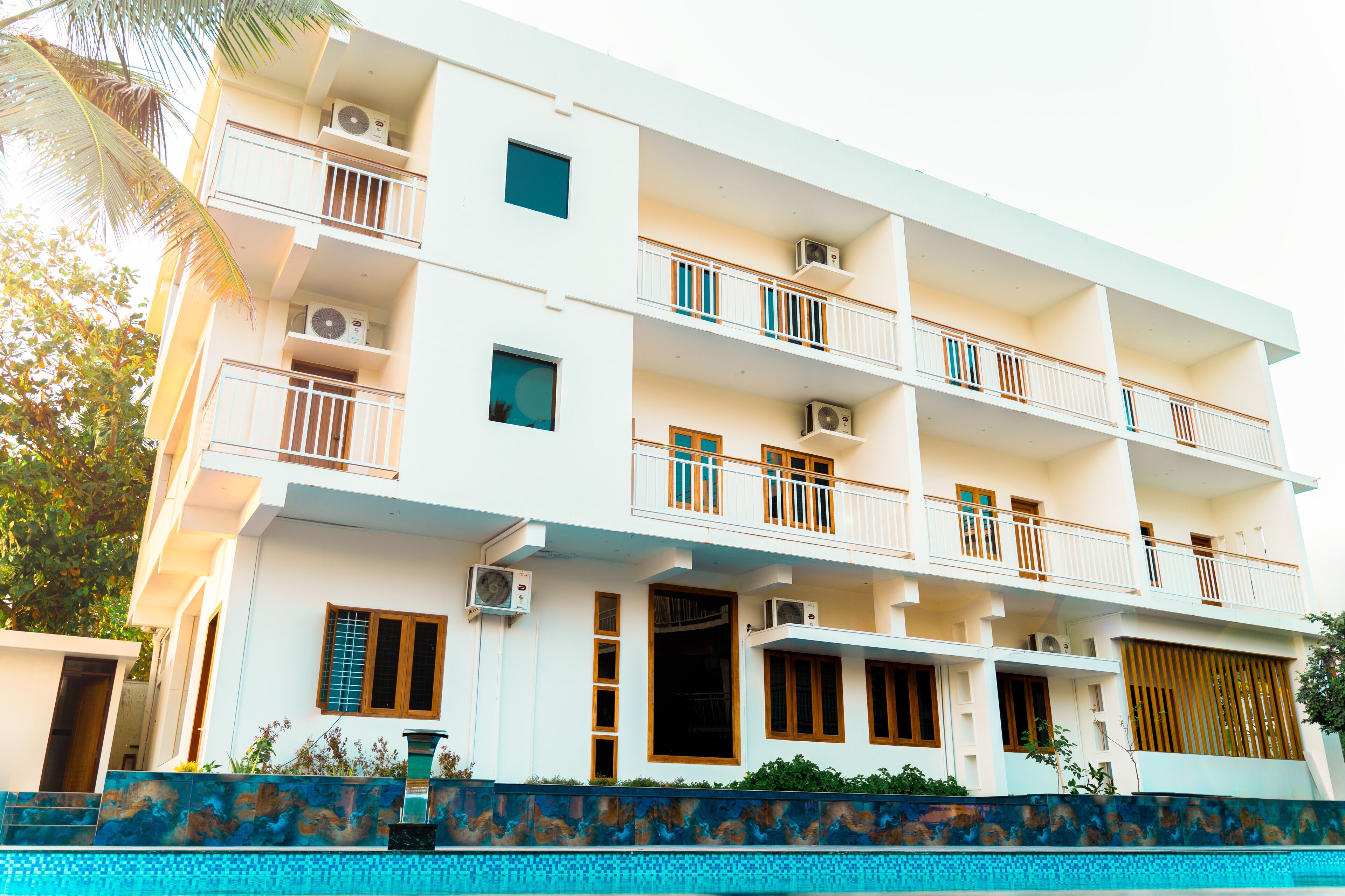 A multi-story hotel with balconies, air conditioning units, and a swimming pool.