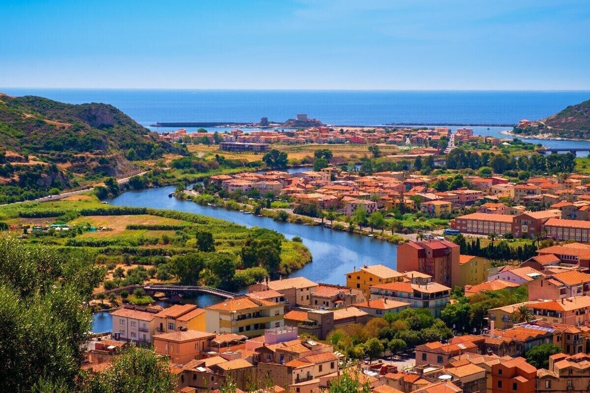 A coastal town with terraced fields, a river, and buildings with red-tiled roofs.